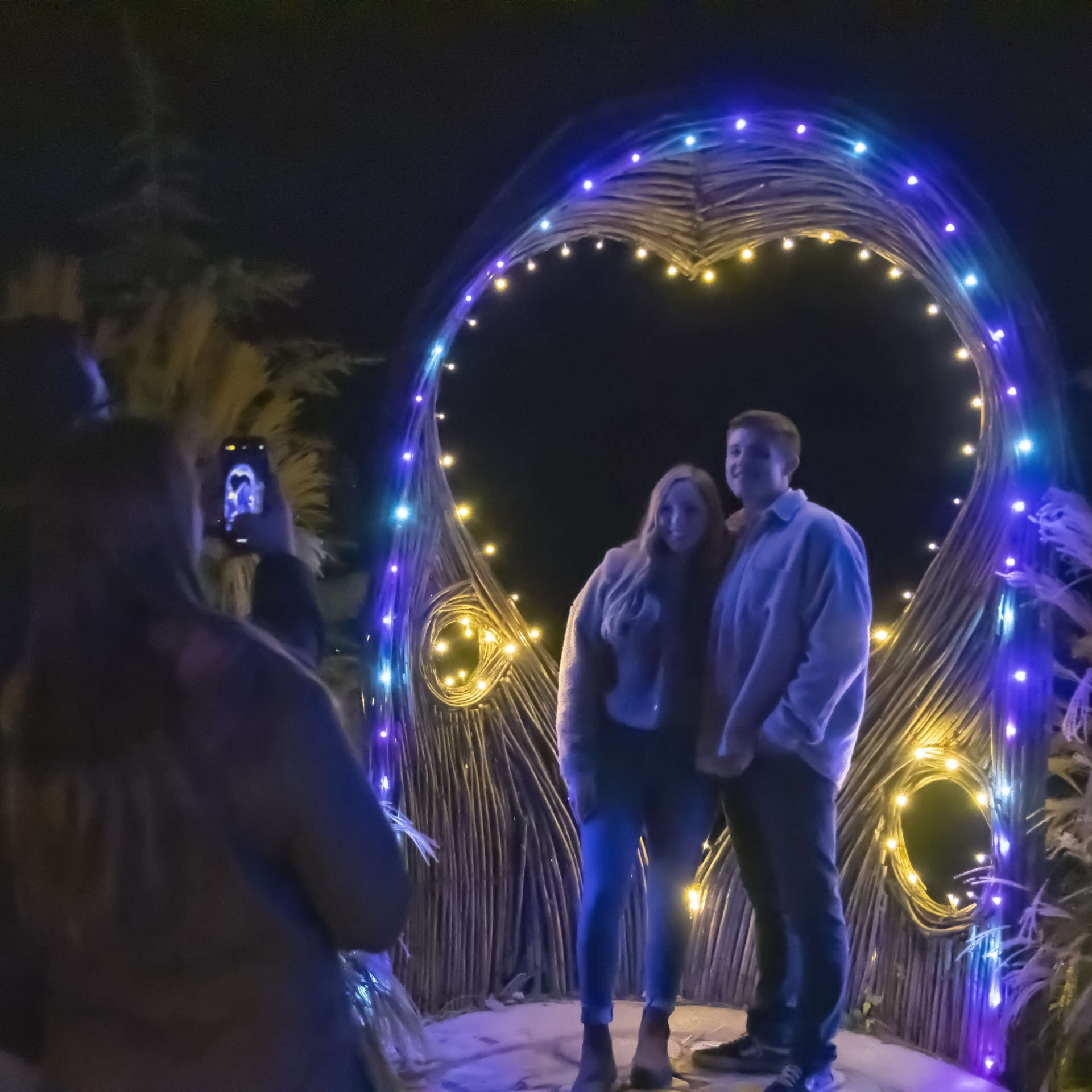 Couple takes picture beneath a heart made out of tree roots at Anakeesta